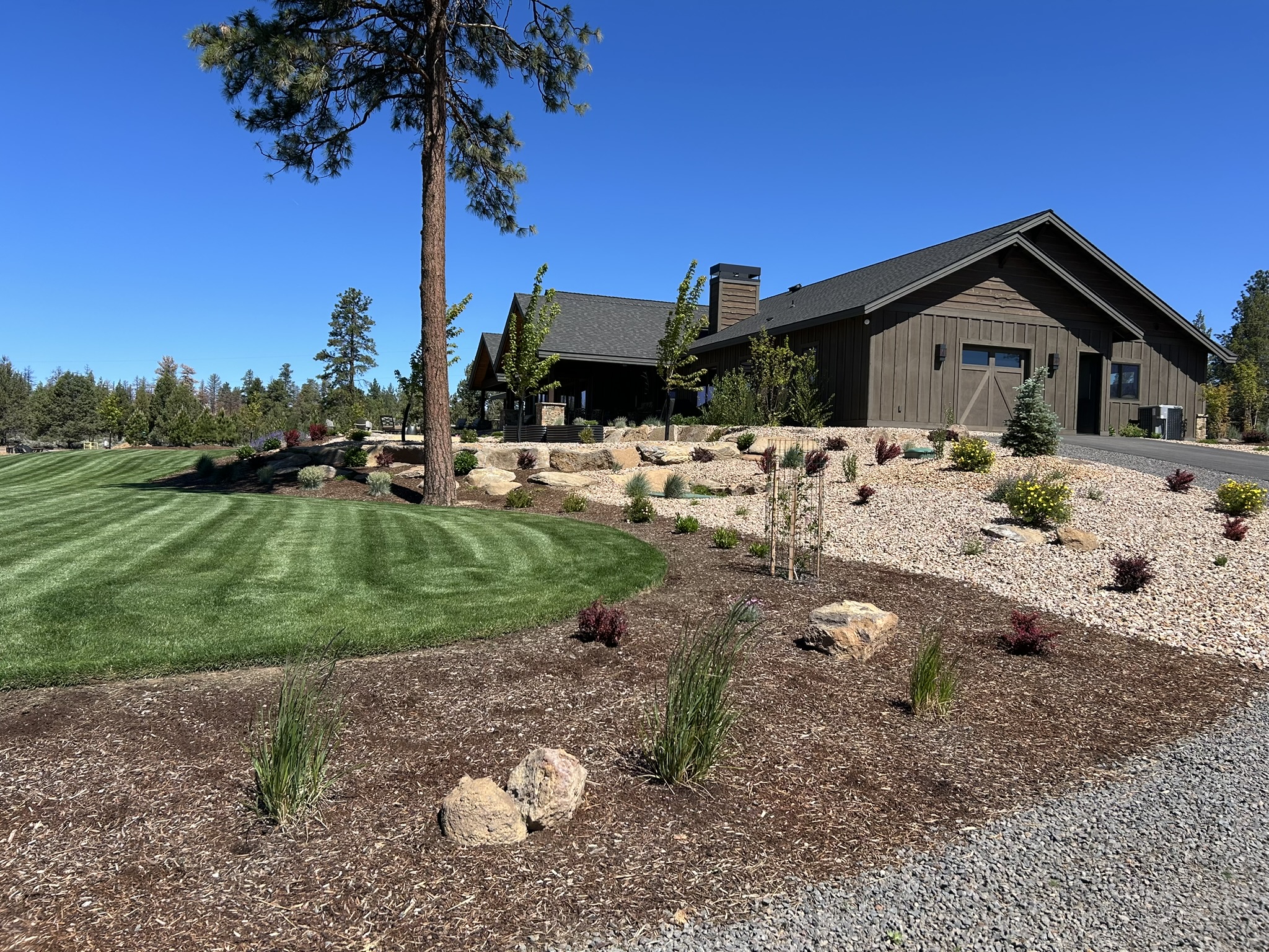 A home in Central Oregon with a beautifully maintained yard and tasteful local shrubs in the front yard.